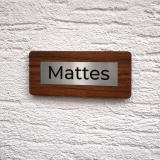 Hochwertige, personalisierte Namensschilder aus massivem Walnussholz mit eingelassenem Inlay aus Acryl in gebürsteter Edelstahloptik und präziser Gravur. Die natürliche Holzstruktur verleiht jedem Schild eine edle und moderne Ausstrahlung und macht es zu
