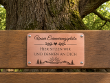 Graviertes Kupferschild für besondere Erinnerungsorte, Gartenbänke und Lieblingsplätze. Das Schild wird mit dem festen Text „Unser Erinnerungsplatz – Hier sitzen wir und denken an Dich“ sowie dekorativem Motiv gefertigt.